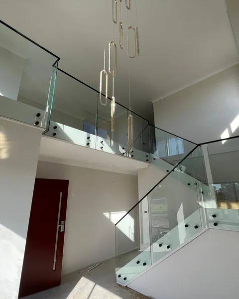 Frameless glass balustrade with matte black handrail around a double-height void