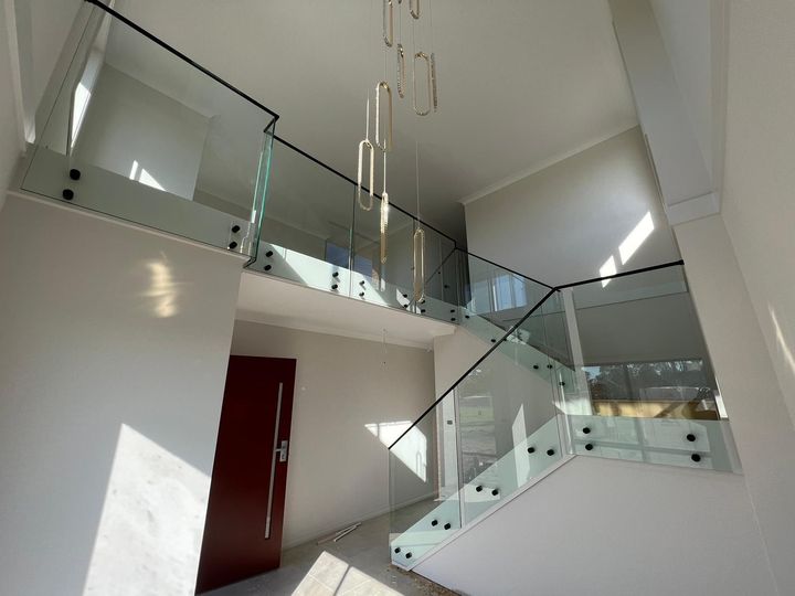 Matte black metal handrail on a glass balustrade in a double-height void