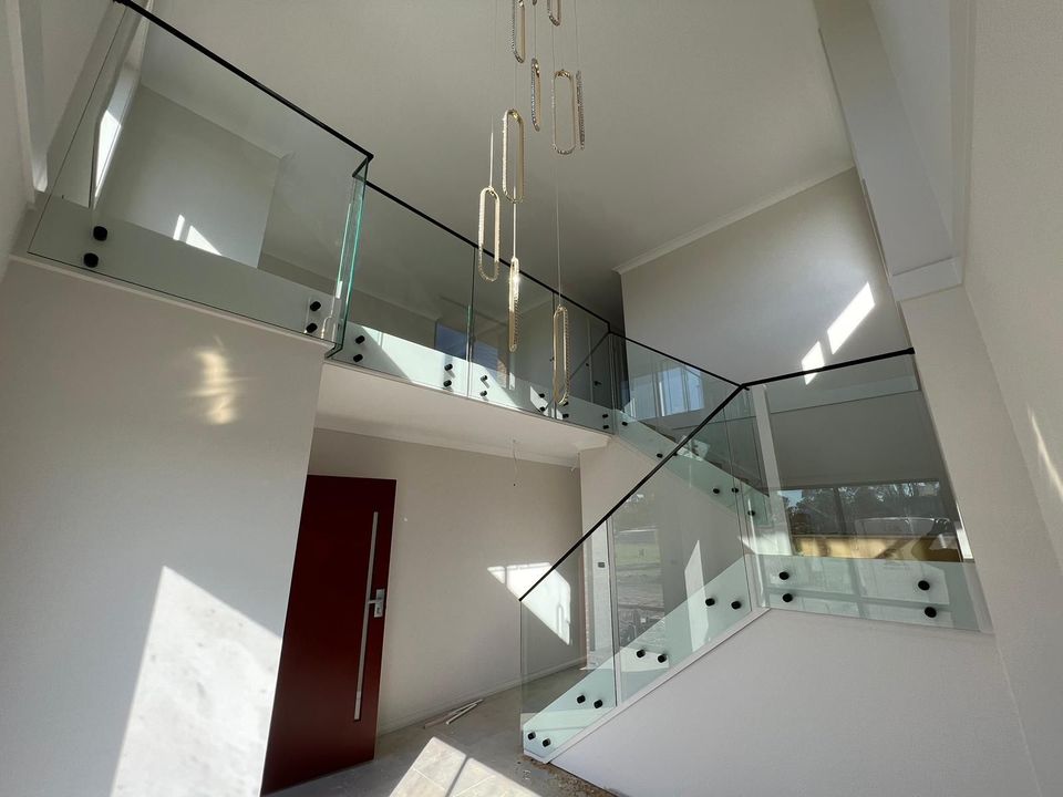 Matte black metal handrail on a glass balustrade in a double-height void