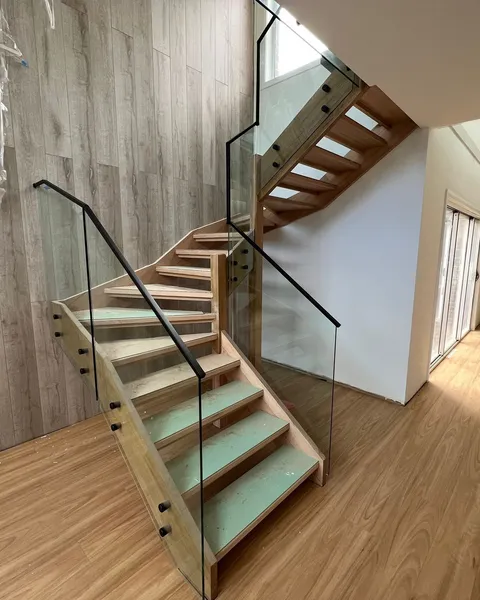 Glass stair balustrade with matte black handrail on timber stairs