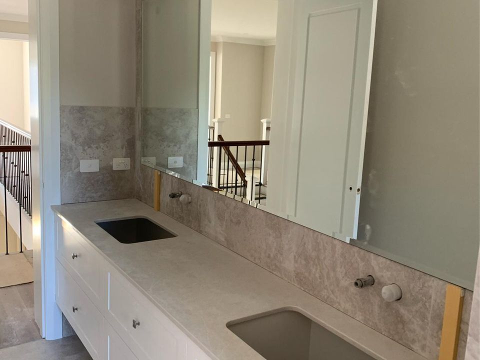 Large custom-cut wall mirror installed above a double vanity