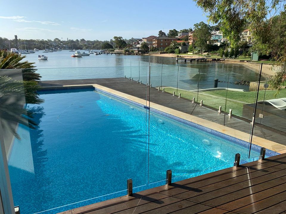 Frameless glass pool fence around a backyard swimming pool